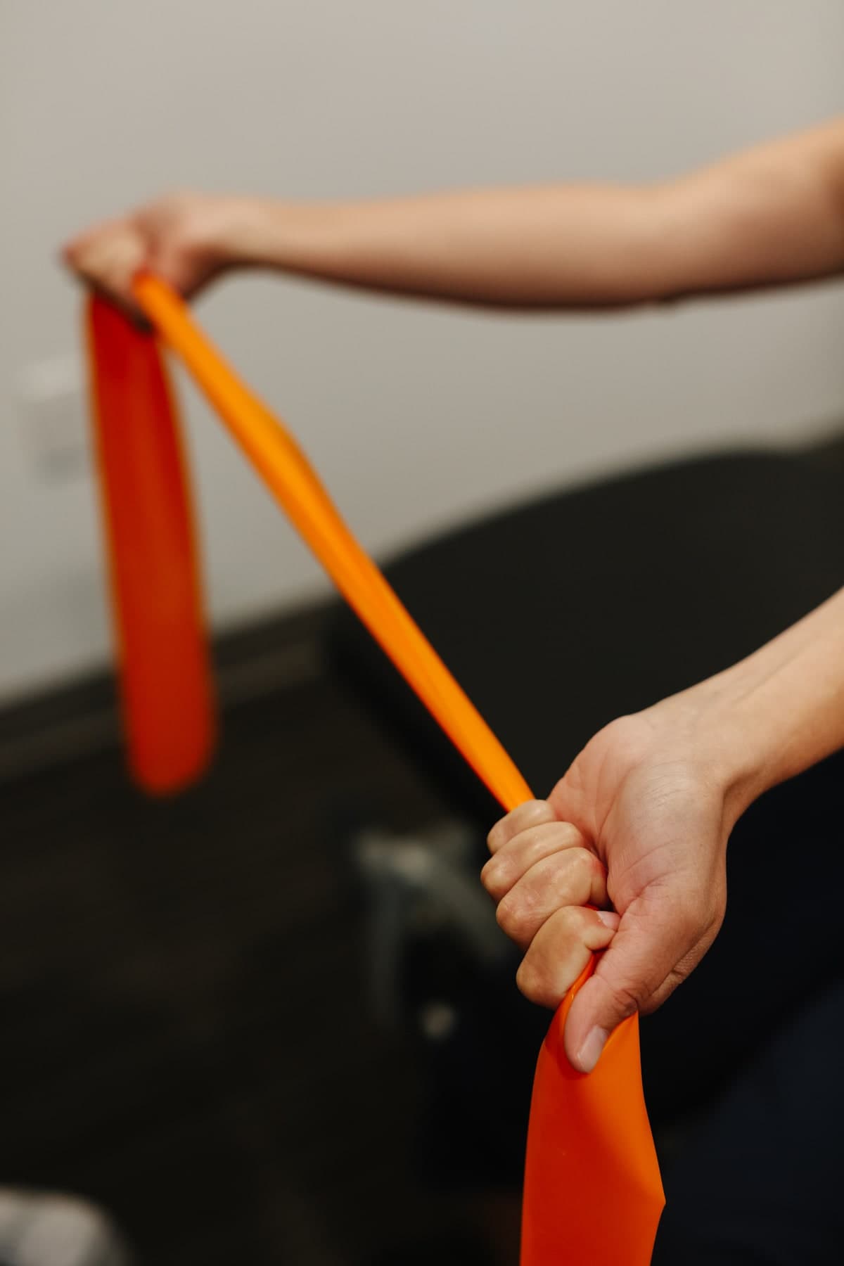 Close-up of a person's hands stretching an orange resistance band in a clinic setting in Swift Current